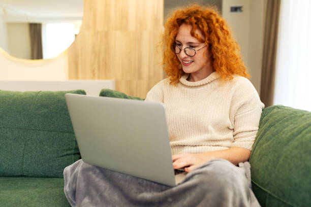 istock Young woman sitting on the floor in her living room while using laptop computer and drinking coffee 2194578764