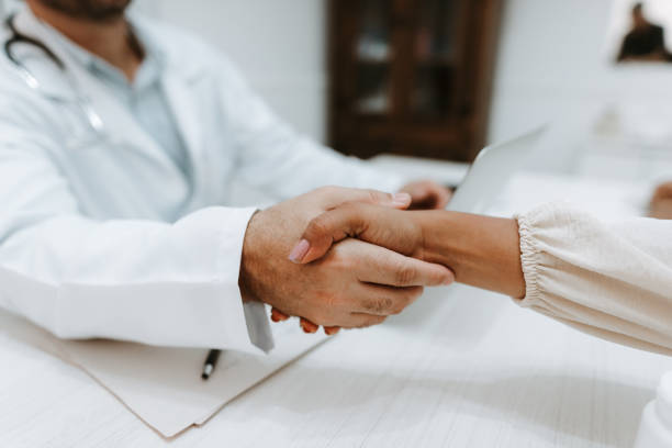 istock Doctor shaking hands with female patient 2194590683