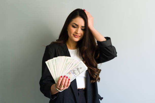 istock Stressed businesswoman holding dollar banknotes and touching head 2194591099