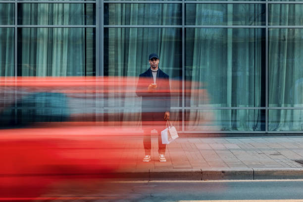 urban scene of man in motion with a passing red vehicle - nieuw fotos stockfoto's en -beelden