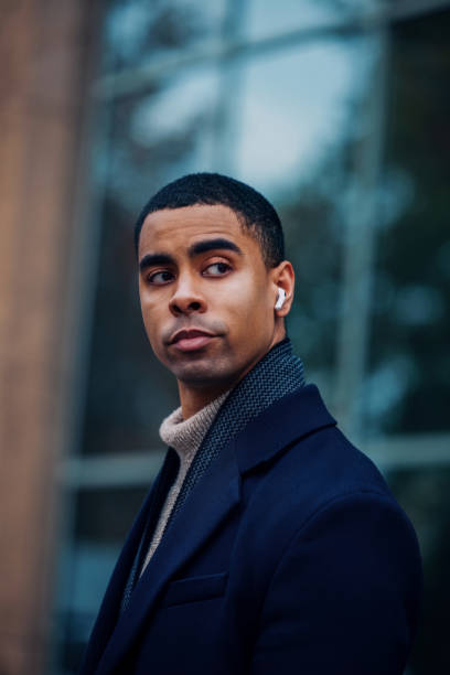 istock Stylish Urban Man Wearing Earbuds and Coat in a Modern Environment 2194591269