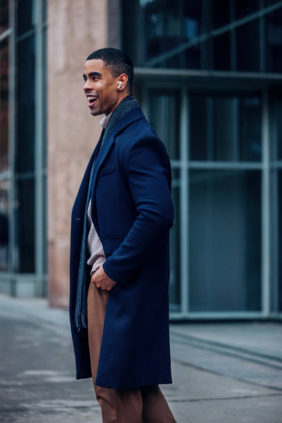 istock Stylish Professional in Winter Coat Smiling Outdoors with Earbuds 2194591285