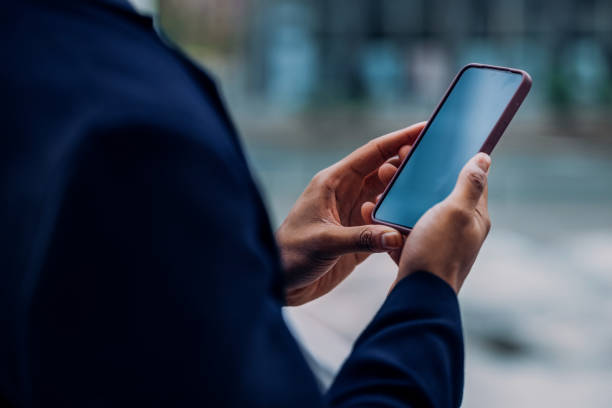 Close-Up of Hands Holding a Smartphone in an Urban Setting