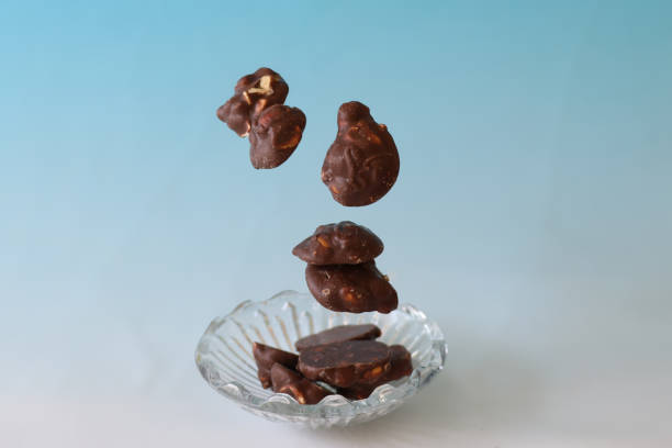 Peanut chocolates in a crystal bowl isolated on a blue background.