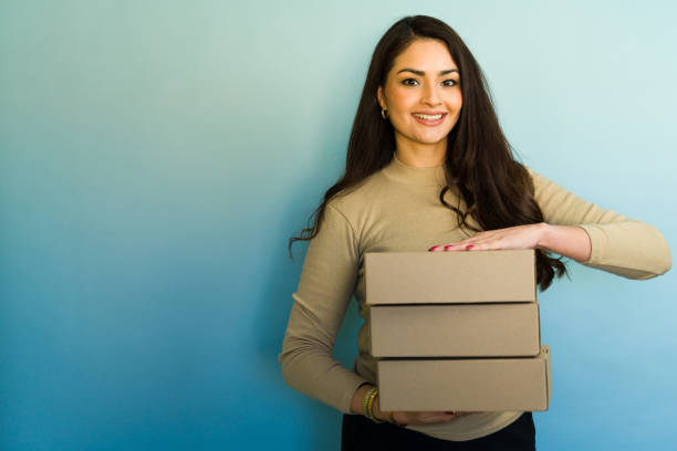 istock Young entrepreneur woman holding a stack of cardboard boxes for shipping 2194591701