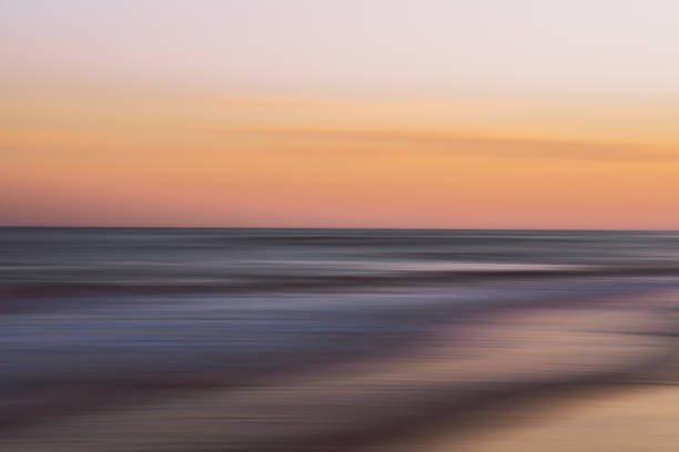 istock Soft sunset hues blur over a calm ocean shoreline. 2194592470