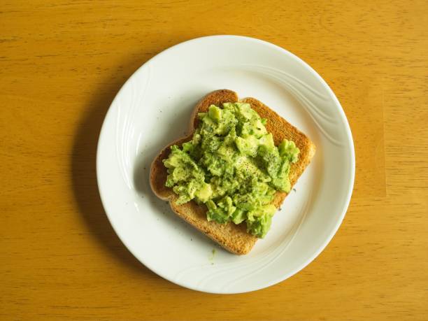 Creamy, delicious and healthy avocado toast for lunch or snack is a trendy food selection, Avocados pack high nutrition, healthy fats and high fiber, served with black peeper and cilantro.