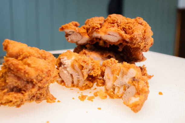 Cutting Korean fried chicken into half, showing white juicy meat inside and a thin crispy skin surface