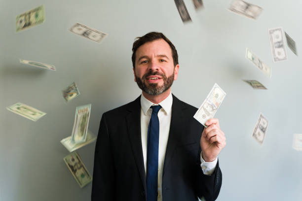 istock Happy businessman holding money with banknotes falling around him 2194597924