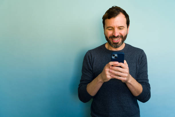 istock Happy man using smartphone on blue background: reading good news and smiling 2194598892