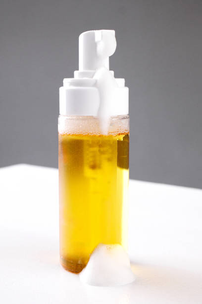 istock Foaming liquid soap bottle on a white surface with bubbles and amber color under bright studio lighting 2194599705