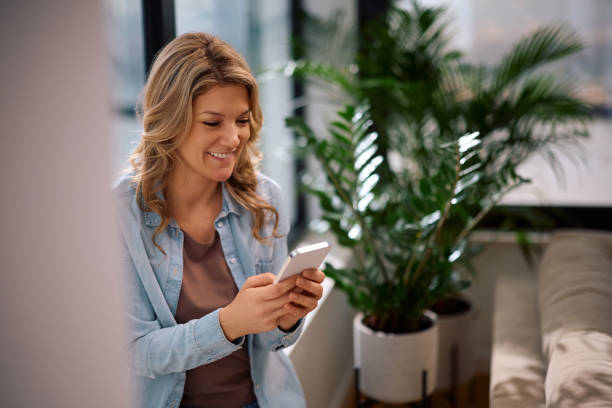 istock Happy woman tying text message on cell phone at home. 2194605153