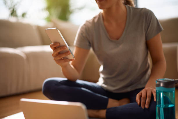 istock Close up of sportswoman using cell phone while working out at home. 2194605192