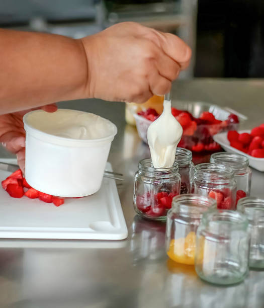 istock Pastry chef pouring yogurt into jars with fresh fruits 2194605784