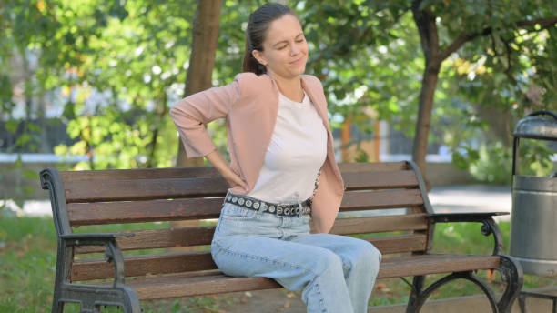 istock Young Woman with Spinal Pain Sitting in Park 2194608121