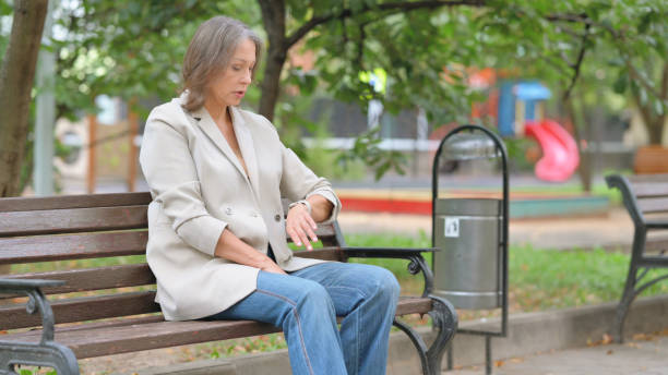 istock Waiting Old Woman Checking Time Sitting Outdoor on Bench 2194610229