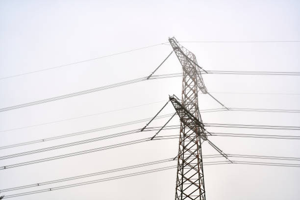Electricity pylon and power lines transporting electricity on a foggy day