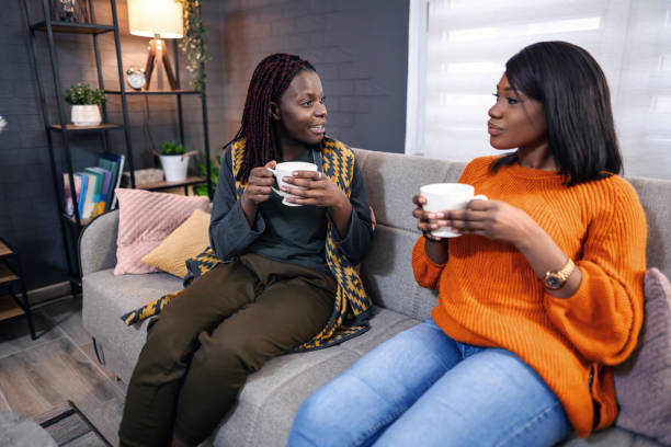istock Two black women relaxing on sofa, drinking tea and chatting 2194610964
