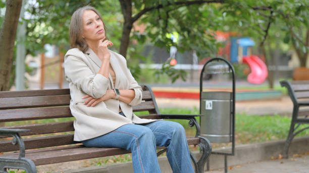 istock Pensive Old Woman Sitting Outdoor on Bench 2194611400
