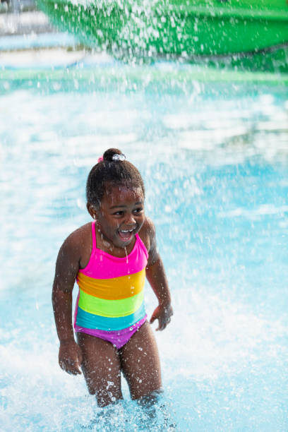 istock African-American girl getting splashed in swimming pool 2194612237