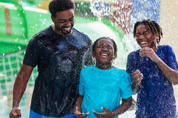istock African-American father, boys get drenched at water park 2194612245