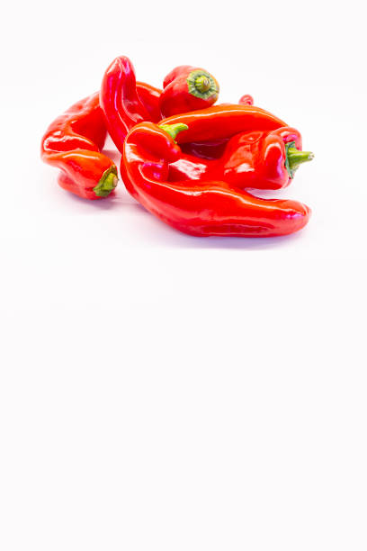 Red capia pepper falling underwater with splashes on black.