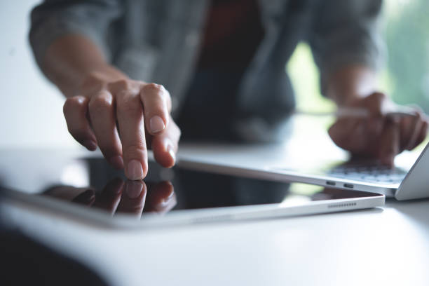 istock Close up, woman using digital tablet and working on laptop computer on office table. Graphic designer using mobile app on tablet, finger touching on screen 2194617000