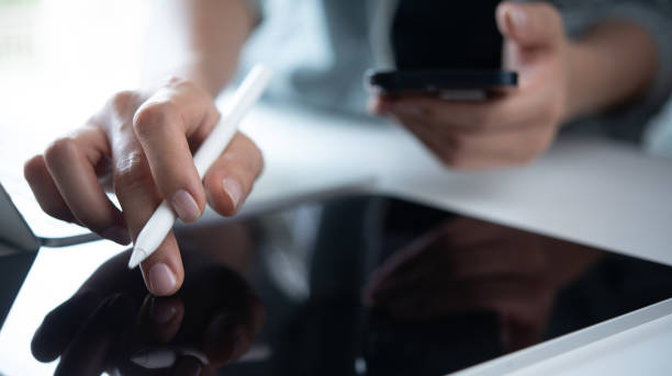 istock Woman using digital tablet and mobile phone, busy working at office, reading e-document, closeup. Freelancer, graphic designer online working via tablet pc on table, work at home, closeup 2194617219