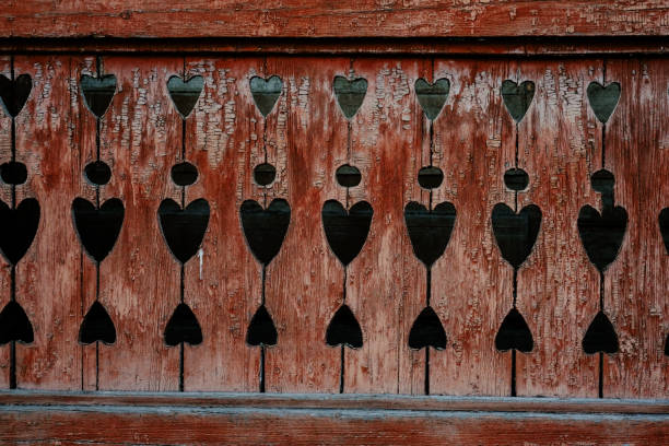 A weathered wooden fence featuring heart-shaped cutouts, showcasing craftsmanship and rustic charm in a bright outdoor environment.