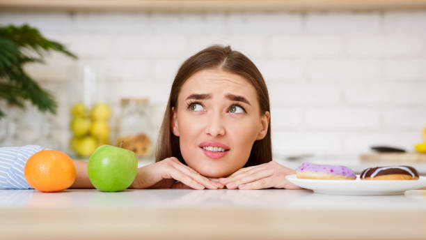 istock Young Woman Choosing Between Fruits and Sweets 2194623470