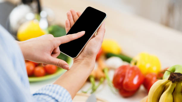 istock Person Using Smartphone in Kitchen Surrounded by Fresh Vegetables and Fruits During Cooking 2194623504