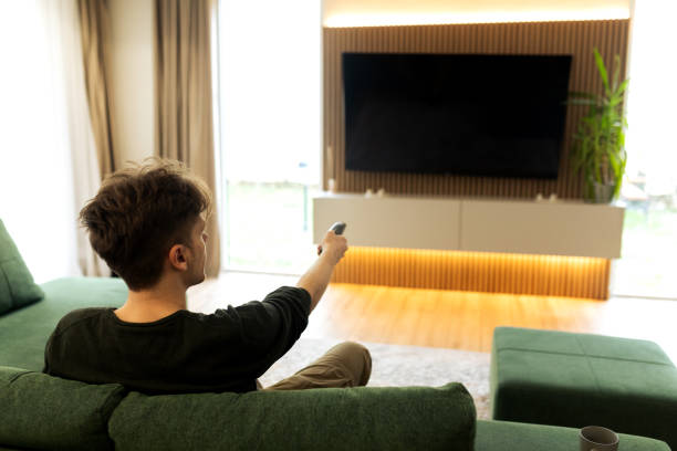 istock Young male using remote to change channel on Television set 2194624171