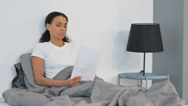 istock African Woman Reading Documents in Bed 2194624284