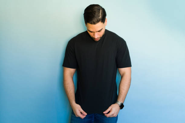istock Pensive man looking down wearing black t-shirt against blue background 2194624317