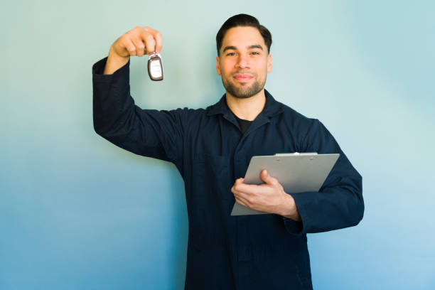 istock Mechanic holding car keys and clipboard on blue background 2194624556