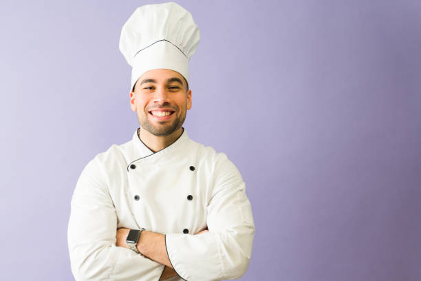 istock Smiling latin chef posing with arms crossed on purple background 2194625107