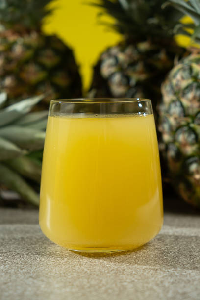 Pineapple juice in a glass among fresh pineapple fruit close-up