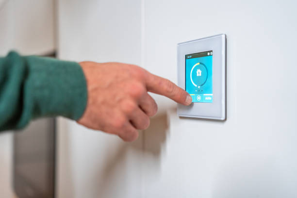 istock Caucasian Male Adjusts Smart Thermostat in Modern Home 2194629772