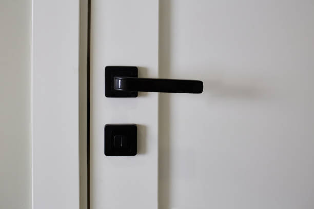 White interior door with black doorknob. Element of interior design, close up.