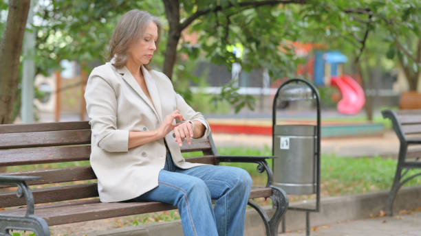 istock Old Woman Waiting while Sitting Outdoor on Bench 2194634506