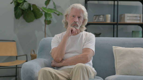 istock Pensive Old Man Sitting on Sofa at Home 2194636379