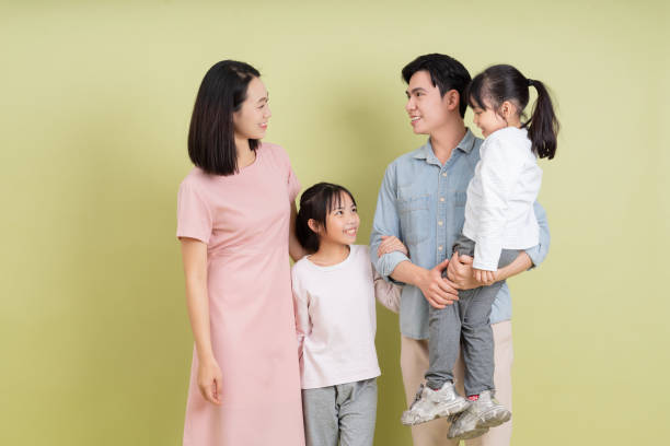 Young Asian family on green background