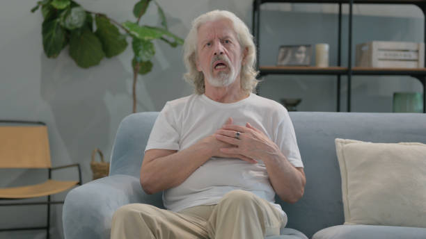 istock Old Man with Chest Pain Sitting on Sofa at Home 2194638600