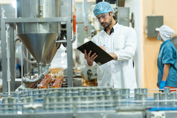 istock Inspector checking automated machinery in food production facility Focus on quality control safety and workflow efficiency. Worker overseeing food packaging machinery in a modern manufacturing plant. 2194644018