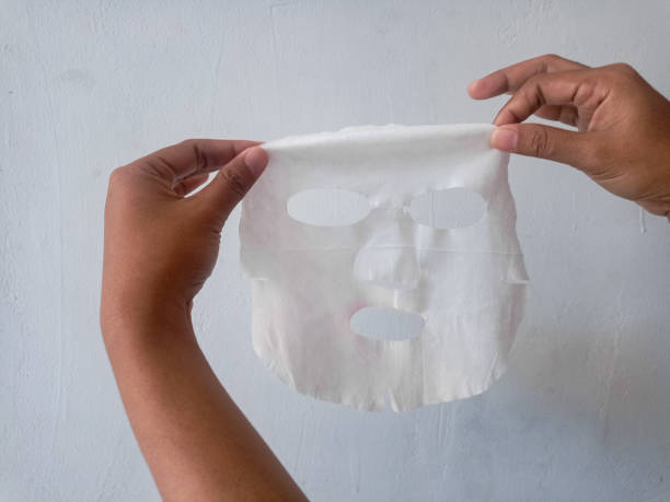 istock Female hands hold fabric sheet mask on gray background. 2194651227