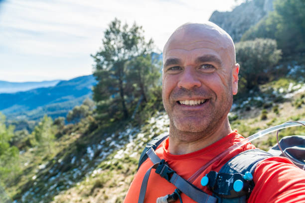 istock Smiling hiker taking a selfie while pointing at mountain peak 2194659006