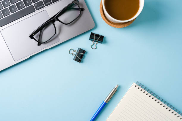 istock Coffee cup, laptop keyboard and notepad on blue office desk. Business office concept 2194659141