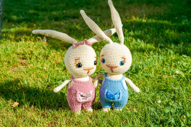 Two toy Easter rabbits on the green grass on a summer day.