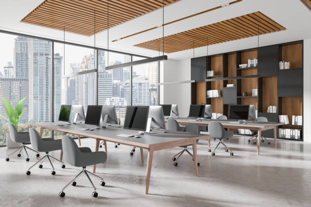 istock Modern open-space office interior with desks, chairs, and computers, featuring a loft design and large windows overlooking a cityscape. 3D Rendering 2194661760
