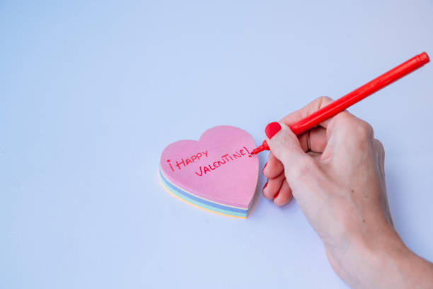 istock A hand is writing on a heart with a red pen. 2194662856